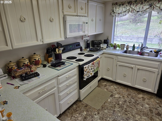 kitchen featuring white microwave, electric range, a sink, light countertops, and white cabinets