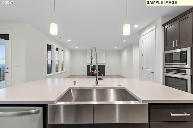 4206 NE 188th St Lot 328, Vancouver, WA 98686 - kitchen with a sink, a warm lit fireplace, light countertops, dark brown cabinets, and appliances with stainless steel finishes