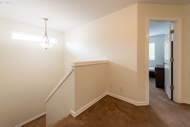 hallway featuring carpet floors, baseboards, and an upstairs landing