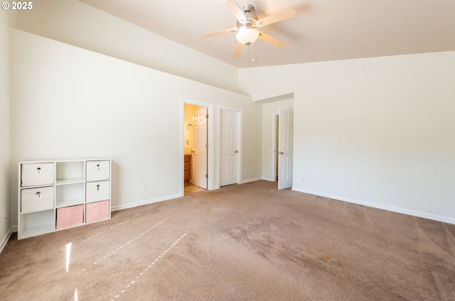 unfurnished bedroom with light colored carpet, baseboards, ensuite bathroom, and lofted ceiling