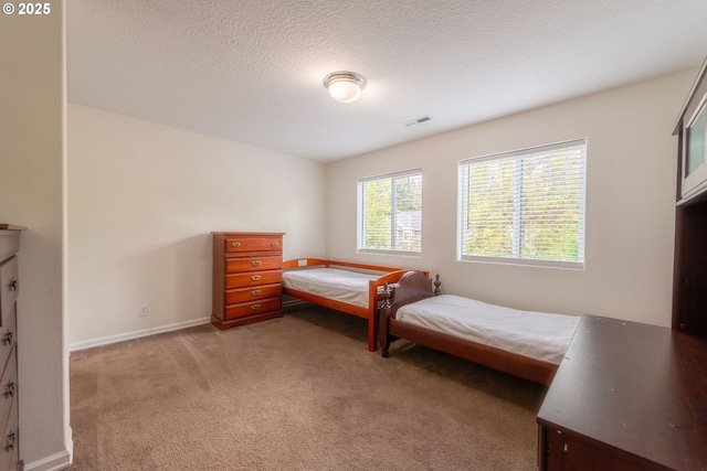bedroom with light colored carpet, baseboards, visible vents, and a textured ceiling