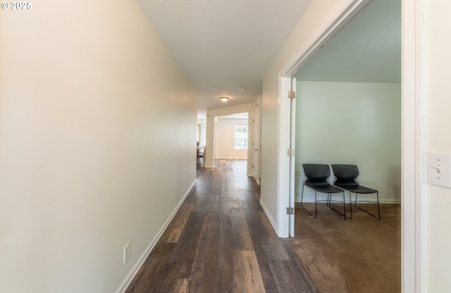 corridor with baseboards, dark wood-style floors, and a textured ceiling