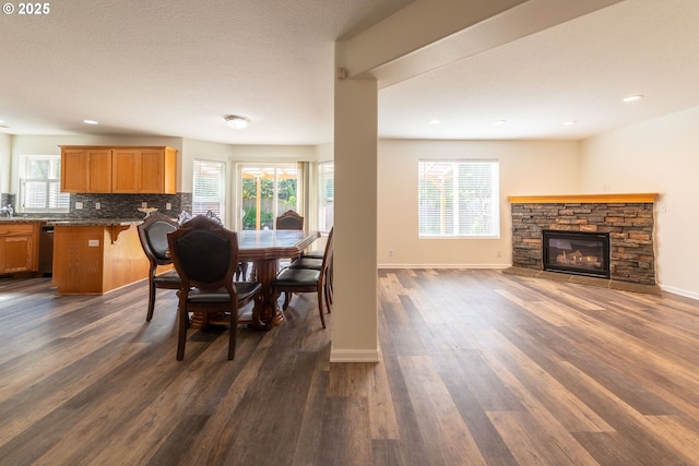 dining room with plenty of natural light, baseboards, dark wood-style floors, and a fireplace