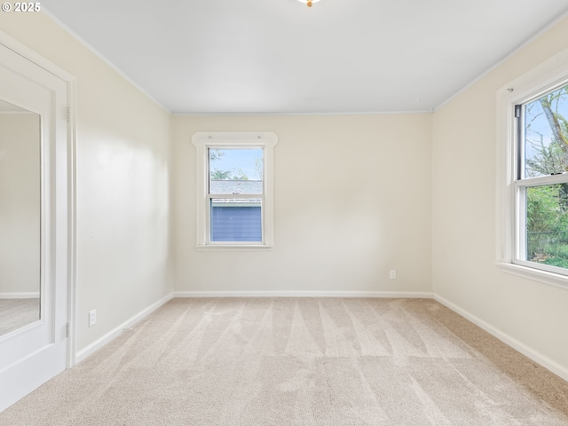 carpeted spare room featuring a healthy amount of sunlight and baseboards