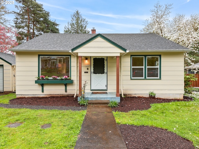 bungalow-style house with a chimney, a shingled roof, and a front yard