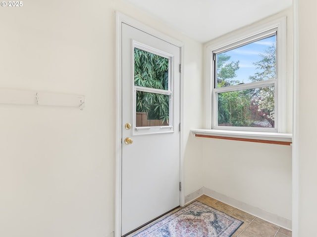 doorway to outside featuring light tile patterned flooring and baseboards