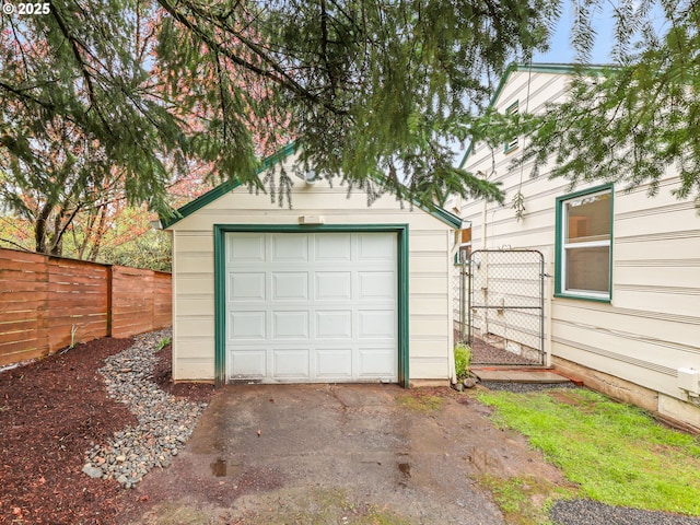 garage featuring aphalt driveway, fence, and a gate