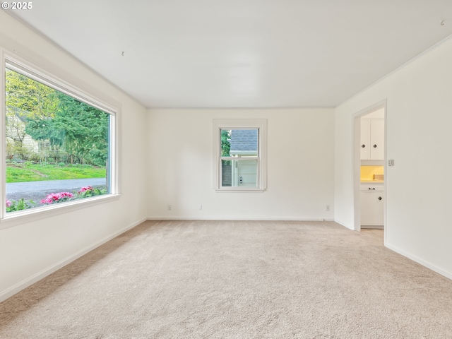 unfurnished room with light colored carpet and baseboards