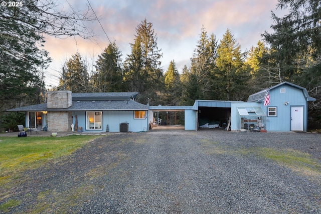 single story home featuring an outdoor structure, central AC unit, and a lawn