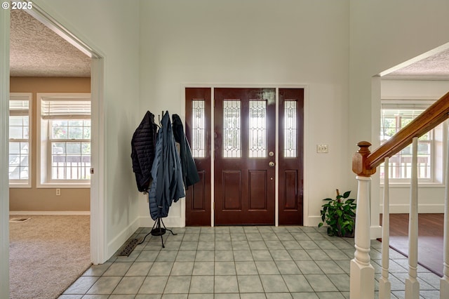 entryway featuring baseboards, light tile patterned floors, stairs, and a high ceiling