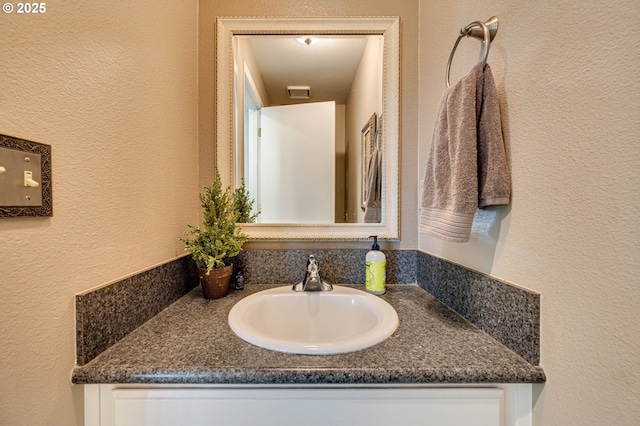 bathroom featuring a textured wall and vanity