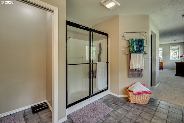 bathroom featuring a stall shower, baseboards, tile patterned floors, and a textured ceiling