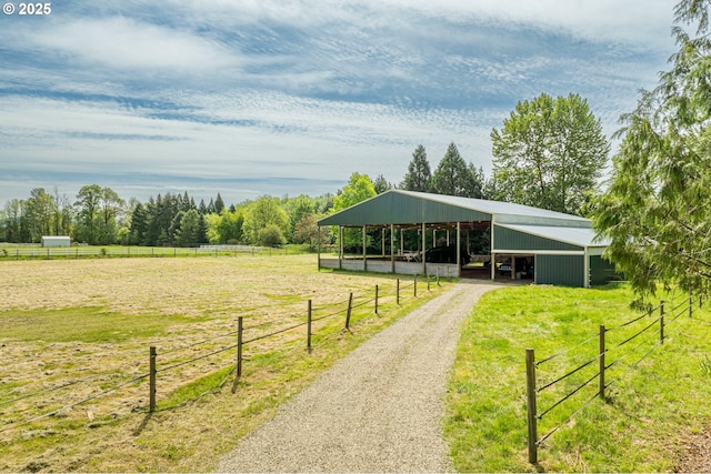 view of home's community with an outbuilding, a view of rural / pastoral area, a detached carport, driveway, and a pole building