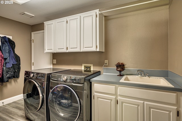 laundry area featuring washer and dryer, cabinet space, wood finished floors, and baseboards