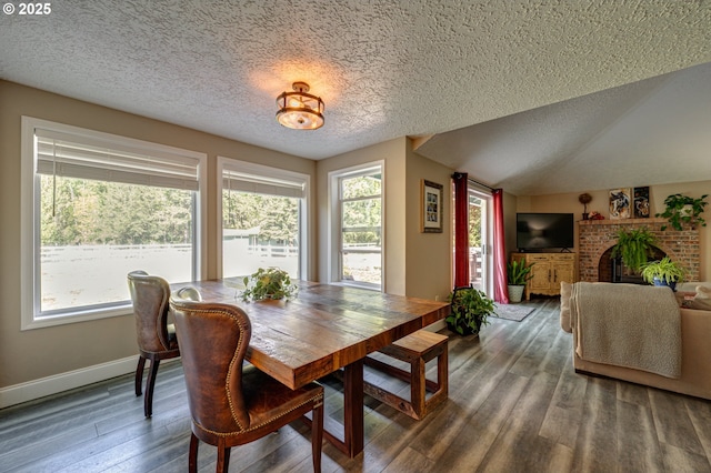 dining room with a textured ceiling, wood finished floors, baseboards, and a fireplace