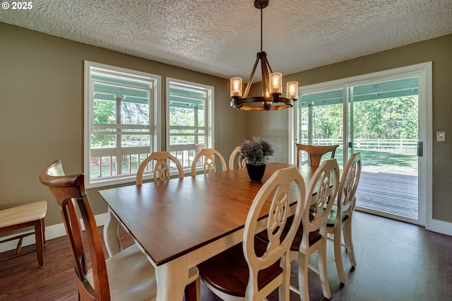 dining space featuring a chandelier, wood finished floors, a textured ceiling, and baseboards