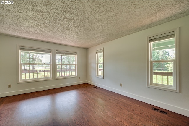 spare room with wood finished floors, baseboards, healthy amount of natural light, and a textured ceiling