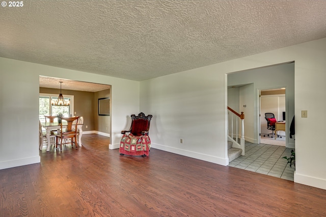 sitting room featuring wood finished floors, a textured ceiling, stairway, baseboards, and a chandelier