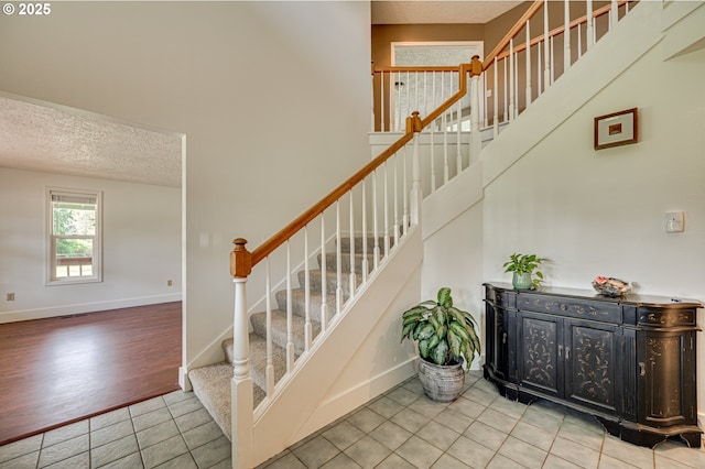 stairs with a textured ceiling, tile patterned floors, and baseboards