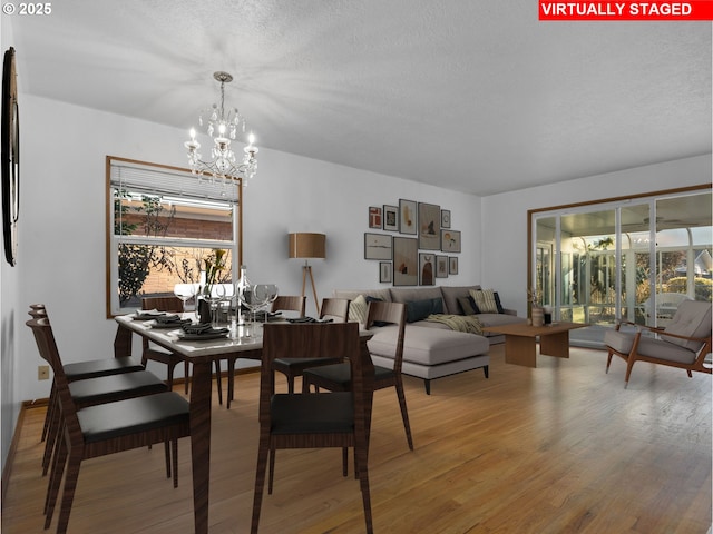 dining area featuring a notable chandelier, light hardwood / wood-style flooring, and a textured ceiling