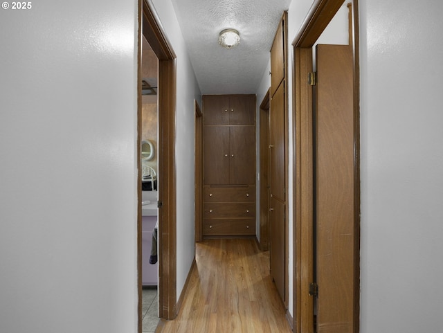 corridor with light hardwood / wood-style floors and a textured ceiling