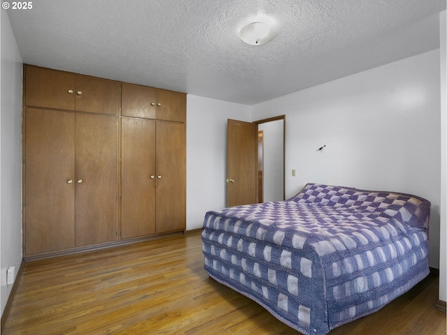 bedroom featuring light hardwood / wood-style floors, a textured ceiling, and a closet