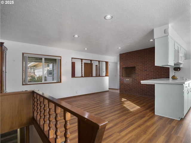 living room with dark wood-type flooring, a textured ceiling, and brick wall