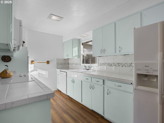 kitchen featuring sink, white appliances, dark hardwood / wood-style floors, and tile counters