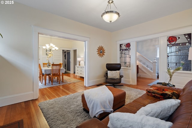 living area with stairs, a chandelier, wood finished floors, and baseboards