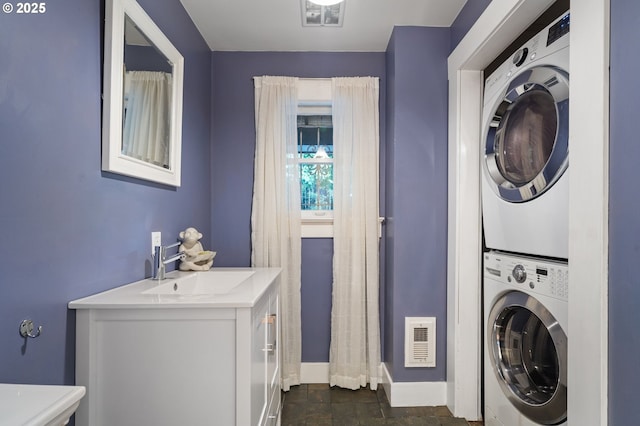 laundry room with stacked washer and clothes dryer, visible vents, a sink, and laundry area