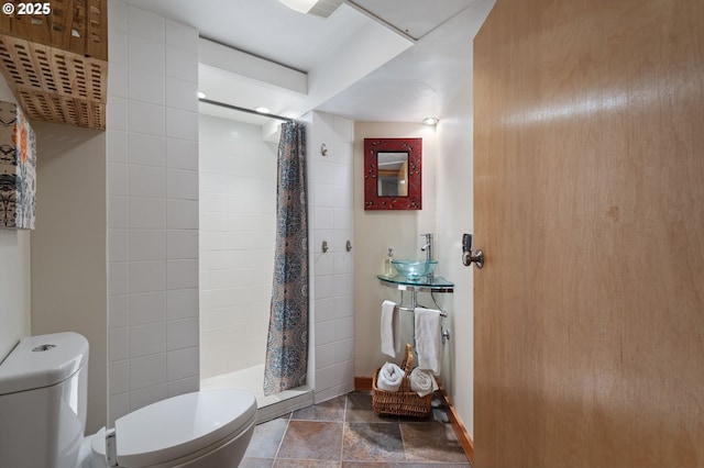 bathroom with a stall shower, baseboards, and toilet