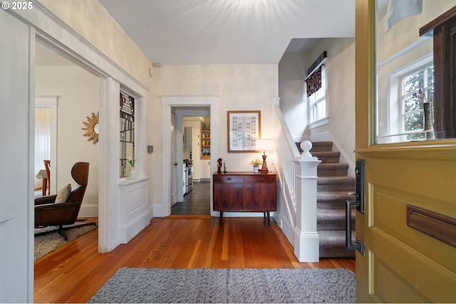 foyer entrance with baseboards, stairway, and wood finished floors