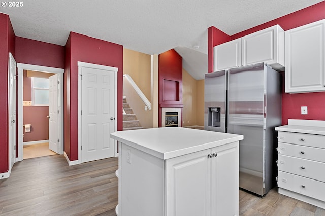 kitchen with white cabinetry, a kitchen island, stainless steel fridge, and light wood-type flooring