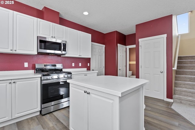 kitchen with stainless steel appliances, a center island, white cabinets, and light wood-type flooring