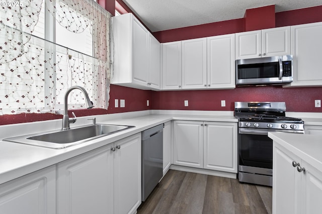 kitchen with white cabinetry, stainless steel appliances, dark wood-type flooring, and sink