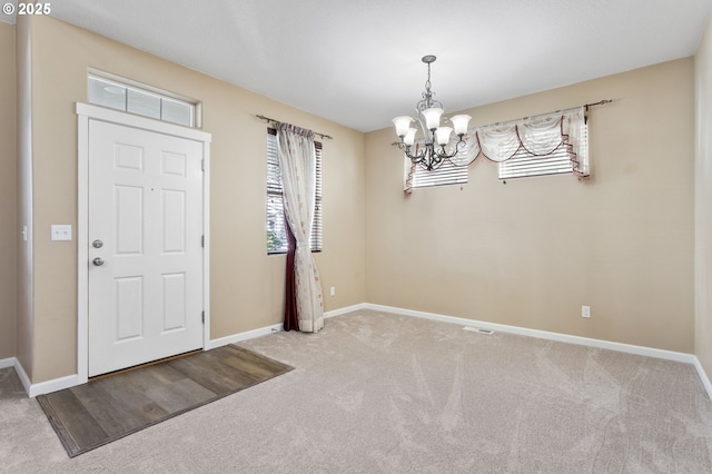 carpeted entrance foyer featuring an inviting chandelier