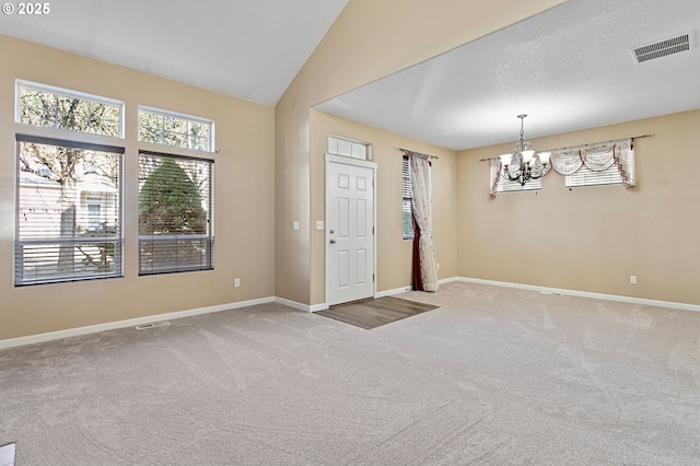 carpeted entryway with lofted ceiling and an inviting chandelier