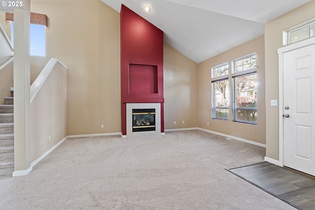 foyer entrance featuring light carpet, high vaulted ceiling, and a tile fireplace