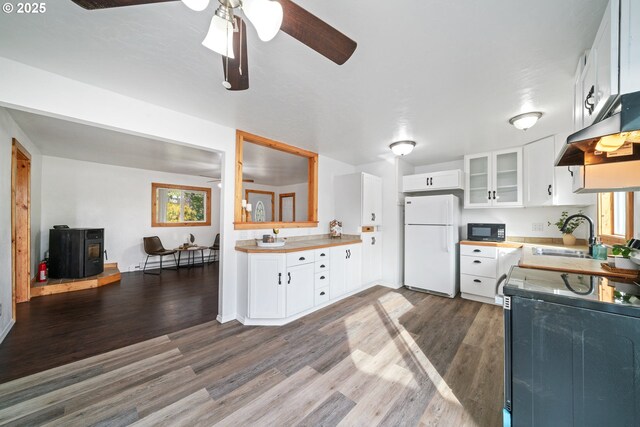 kitchen featuring dark wood-type flooring, black microwave, range, freestanding refrigerator, and a sink