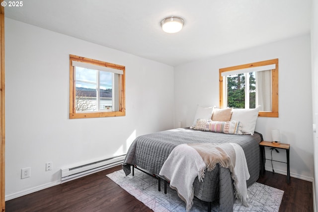 bedroom with multiple windows, wood finished floors, baseboards, and a baseboard radiator