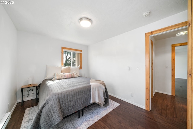 bedroom featuring a baseboard heating unit, baseboards, and wood finished floors