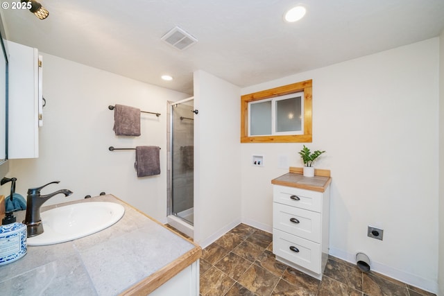 bathroom featuring vanity, baseboards, visible vents, and a stall shower