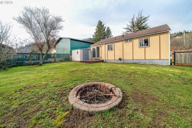 back of house with a yard, stucco siding, a storage unit, and a fenced backyard