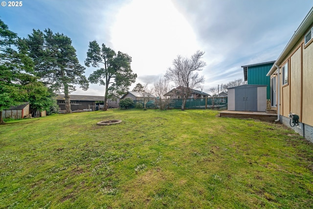 view of yard with an outbuilding, an outdoor fire pit, a fenced backyard, and a shed