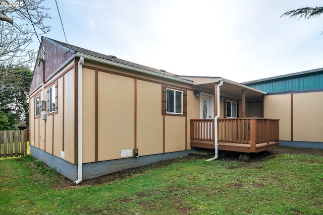 view of side of home featuring a yard, a deck, and fence