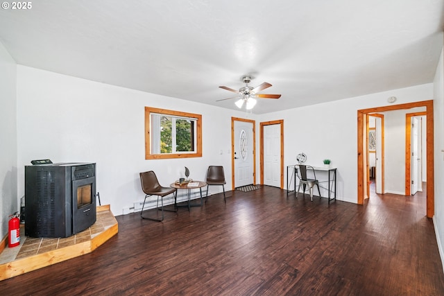 living area with ceiling fan, a baseboard radiator, wood finished floors, and a wood stove