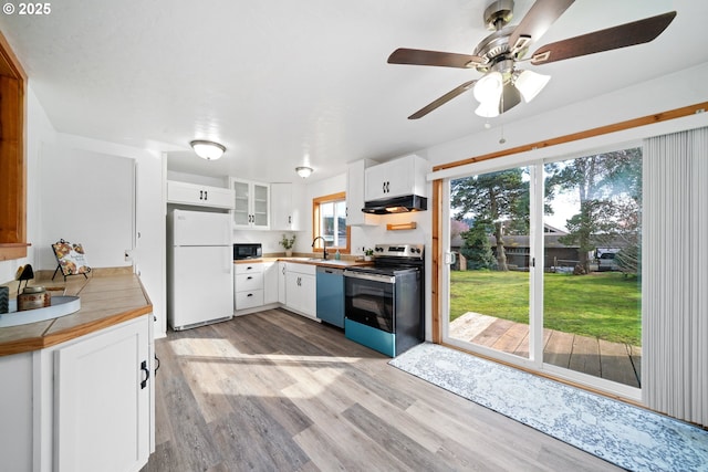 kitchen featuring black microwave, under cabinet range hood, dishwashing machine, stainless steel electric range, and freestanding refrigerator