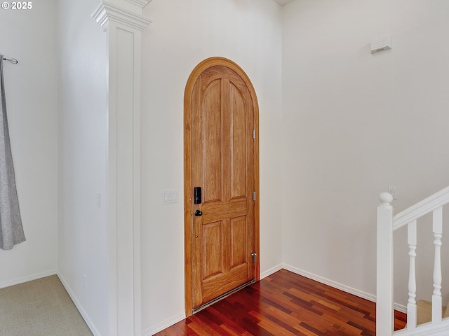 entryway with arched walkways, ornate columns, wood finished floors, and baseboards