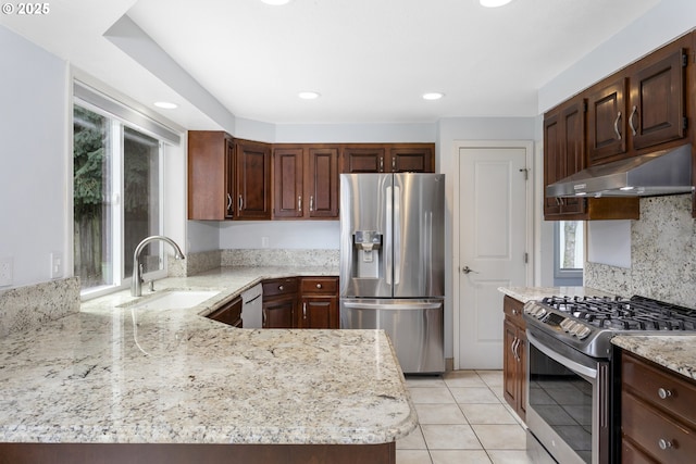 7134 SW 184th Pl, Beaverton, OR 97007 - kitchen with stainless steel appliances, under cabinet range hood, light stone counters, light tile patterned floors, and recessed lighting
