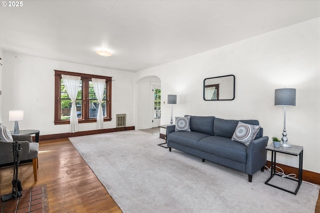 living area featuring arched walkways, wood finished floors, and baseboards